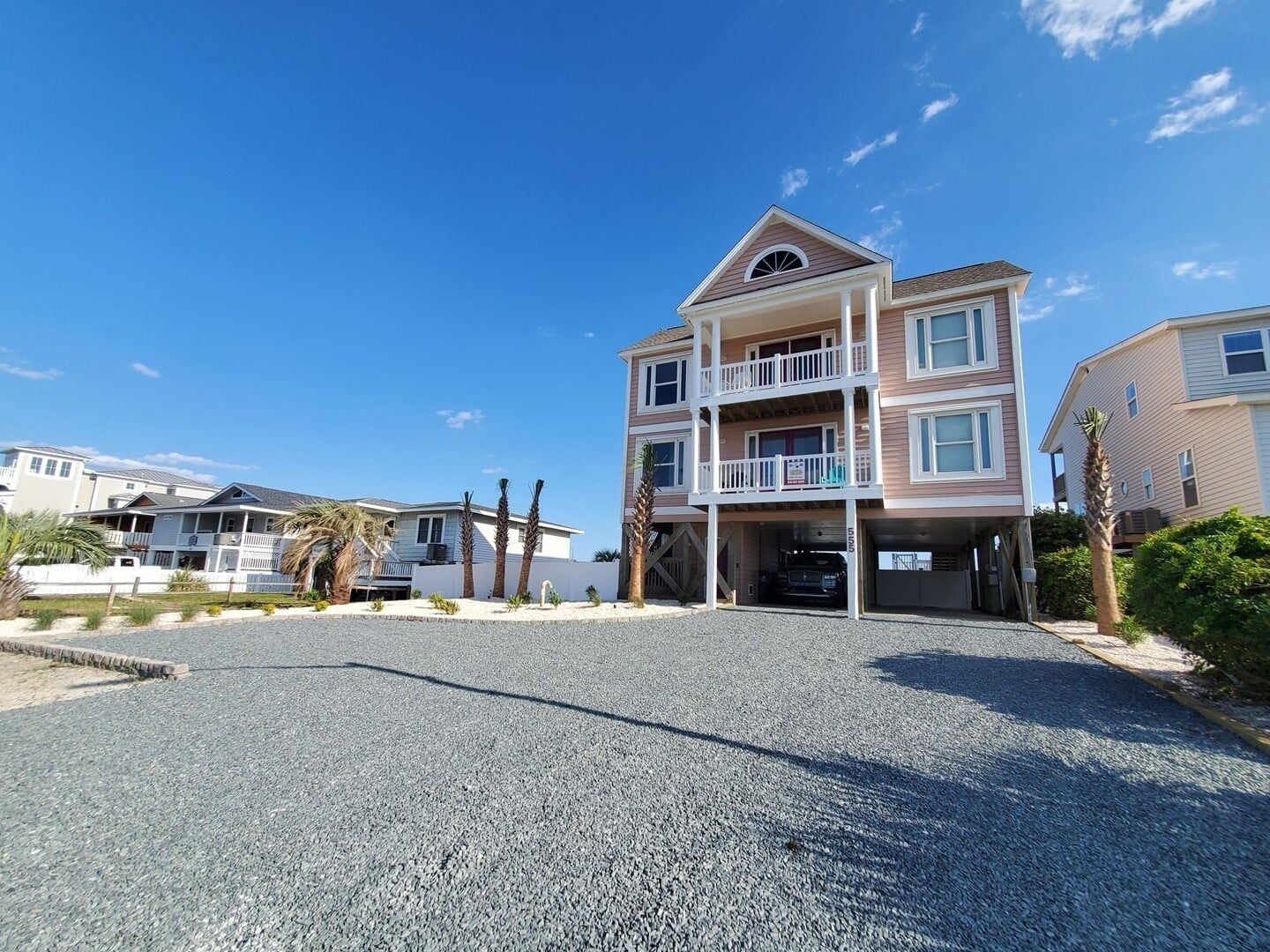 A multi-story residential building with a two-story balcony, a garage, and a driveway.