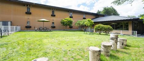 A courtyard with a building, outdoor seating, and trees.