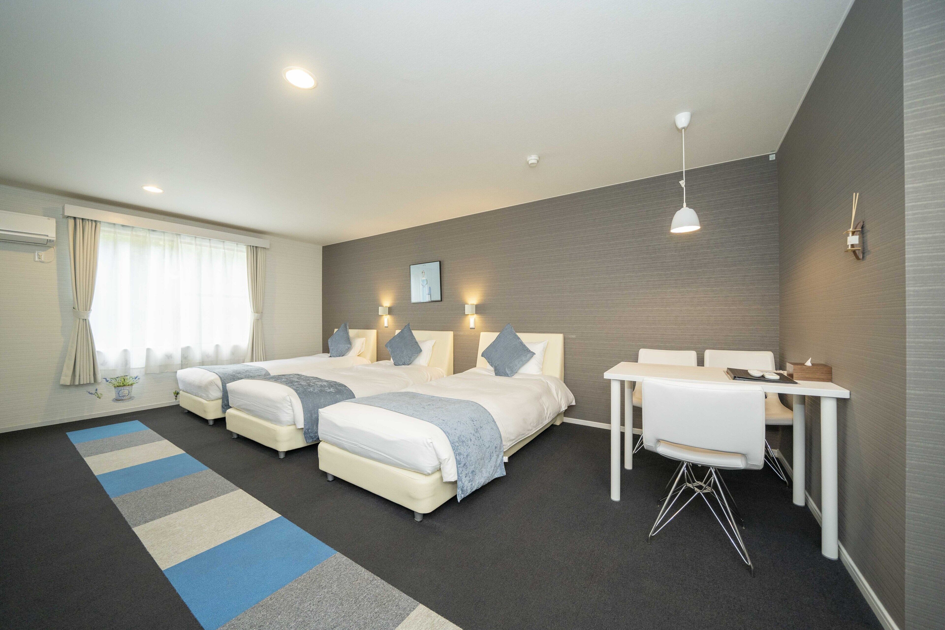 A hotel room with two beds, a desk, and a chair.