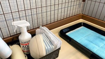 A bathroom with a bathtub, a white bottle of Super AD spray, and a basket of folded towels.