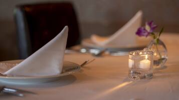 A table set with a folded napkin, a candle in a glass holder, and a small vase with a flower.