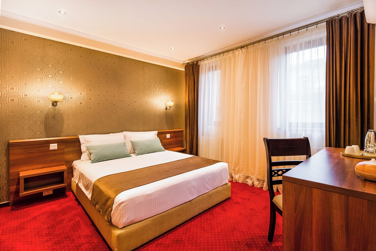 Una habitación de hotel con una cama grande, un escritorio y una silla.