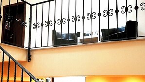 Un interior con varios niveles, una escalera, un comedor con una mesa y sillas rojas, y un cuadro colgado en la pared.