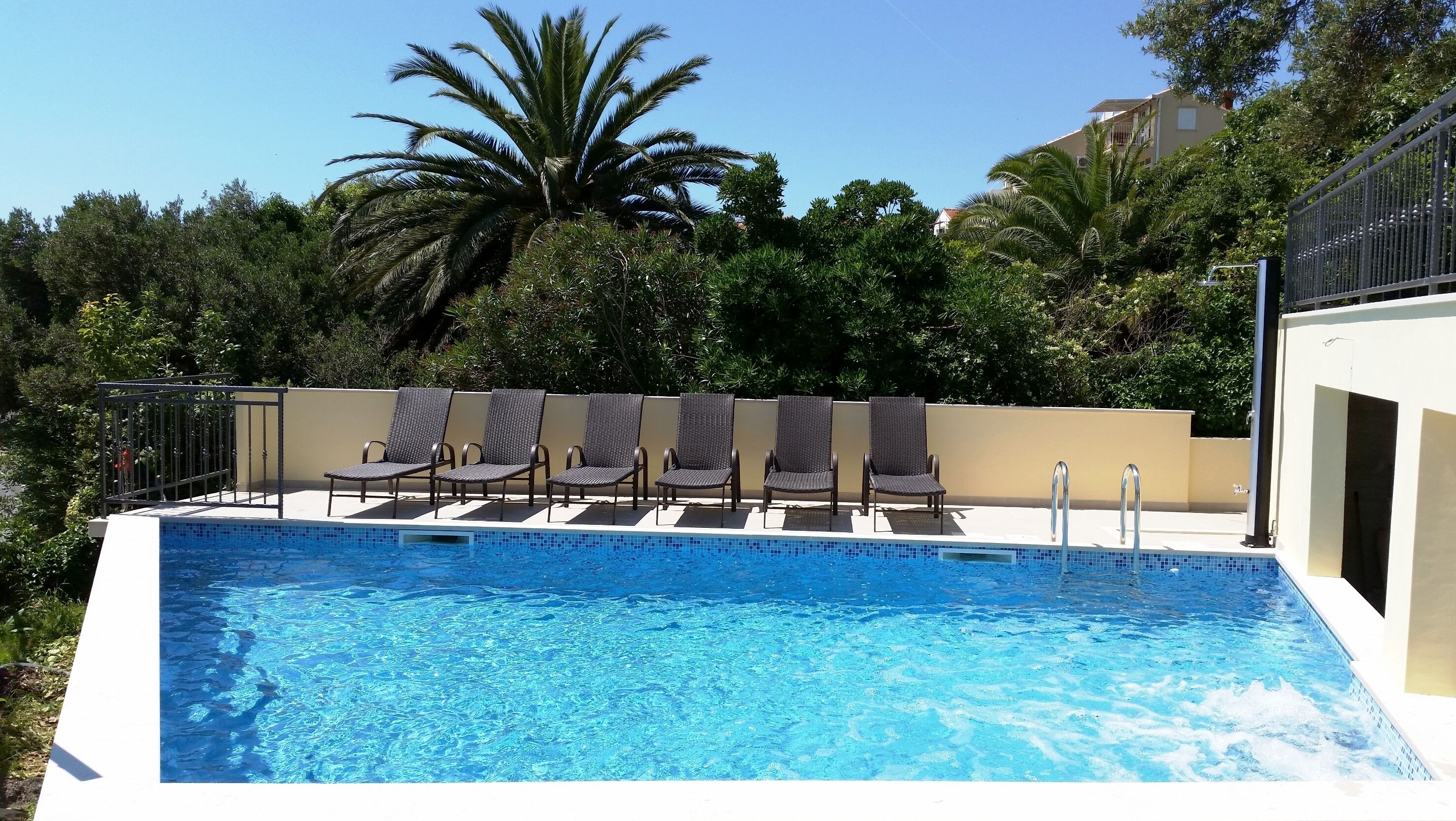 Une piscine avec six chaises longues et une rambarde en métal.