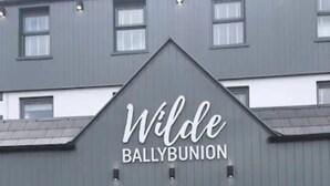 A building with a grey facade and a white door. The sign above the door reads "Wilde Ballybunion". - Wilde Ballybunion (Ballybunion)