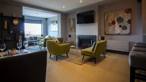 A modern living room with a fireplace, yellow armchairs, a flat-screen TV, and a large abstract painting on the wall. - Wilde Ballybunion (Ballybunion)