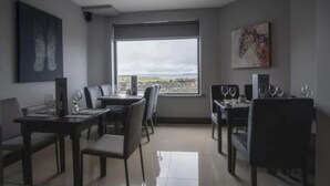 A modern dining area with a large window, dining tables, chairs, and artwork on the walls. - Wilde Ballybunion (Ballybunion)