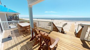 A wooden deck with a table and chairs, overlooking a beach. - Spacious 4 Bedroom Gulf Front Home with large deck overlooking Gulf of Mexico (Port Saint Joe)