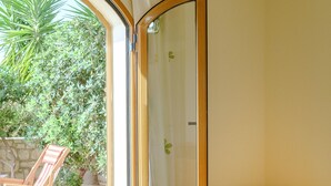 Ein Schlafzimmer mit einer Schiebetür zu einer Terrasse, auf der sich ein Stuhl und Pflanzen befinden.