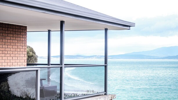 A modern building with a balcony overlooking a coastal view. - Stones Throw - Holiday Houses Tasmania (Primrose Sands)