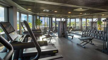 A gym with treadmills, weight machines, and dumbbells.