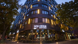 Un hotel moderno con fachada curva, ventanas grandes y un letrero que dice "SANA BERLIN".