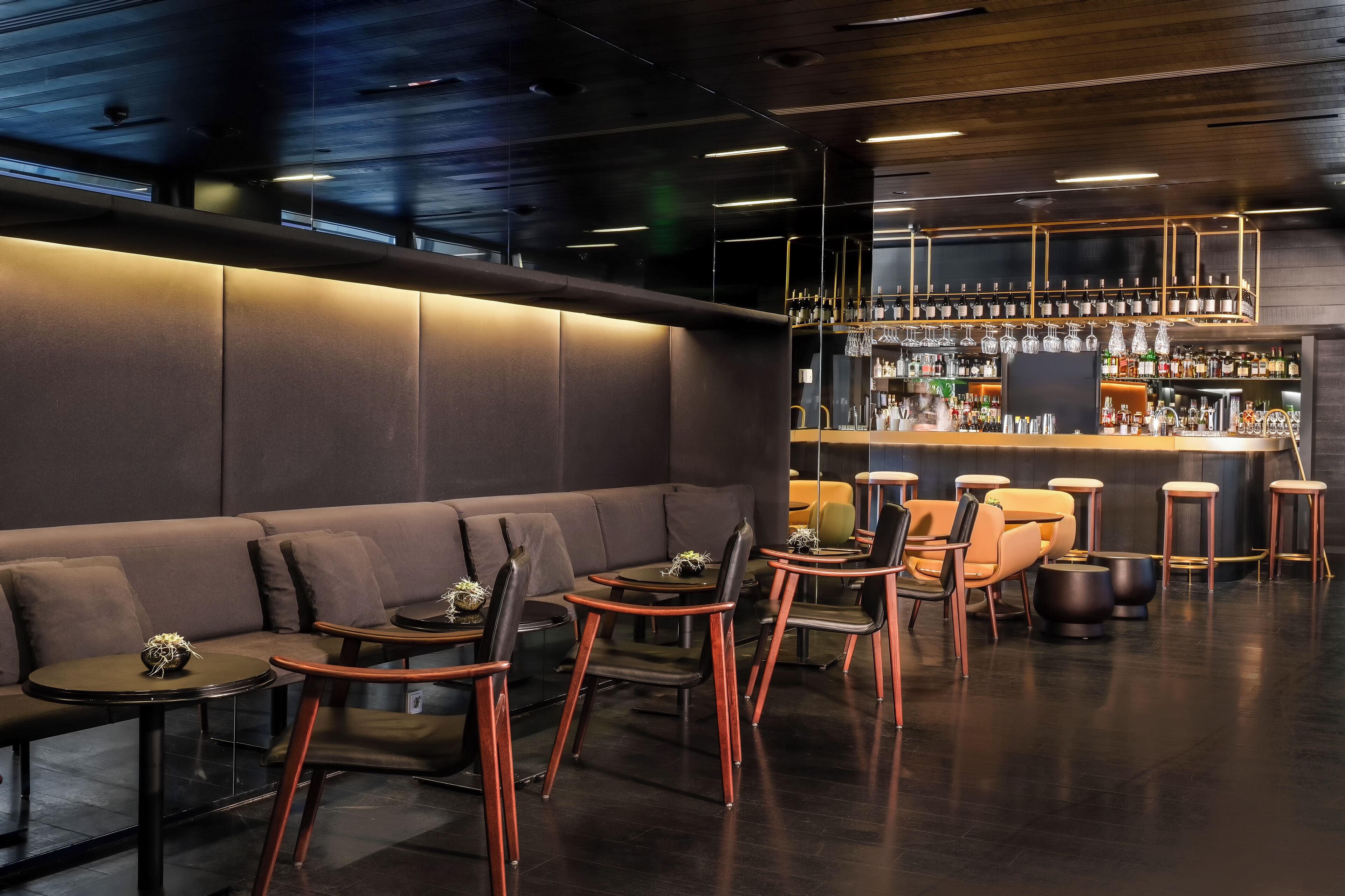 Un espace bar moderne, doté de sièges et d’un comptoir.