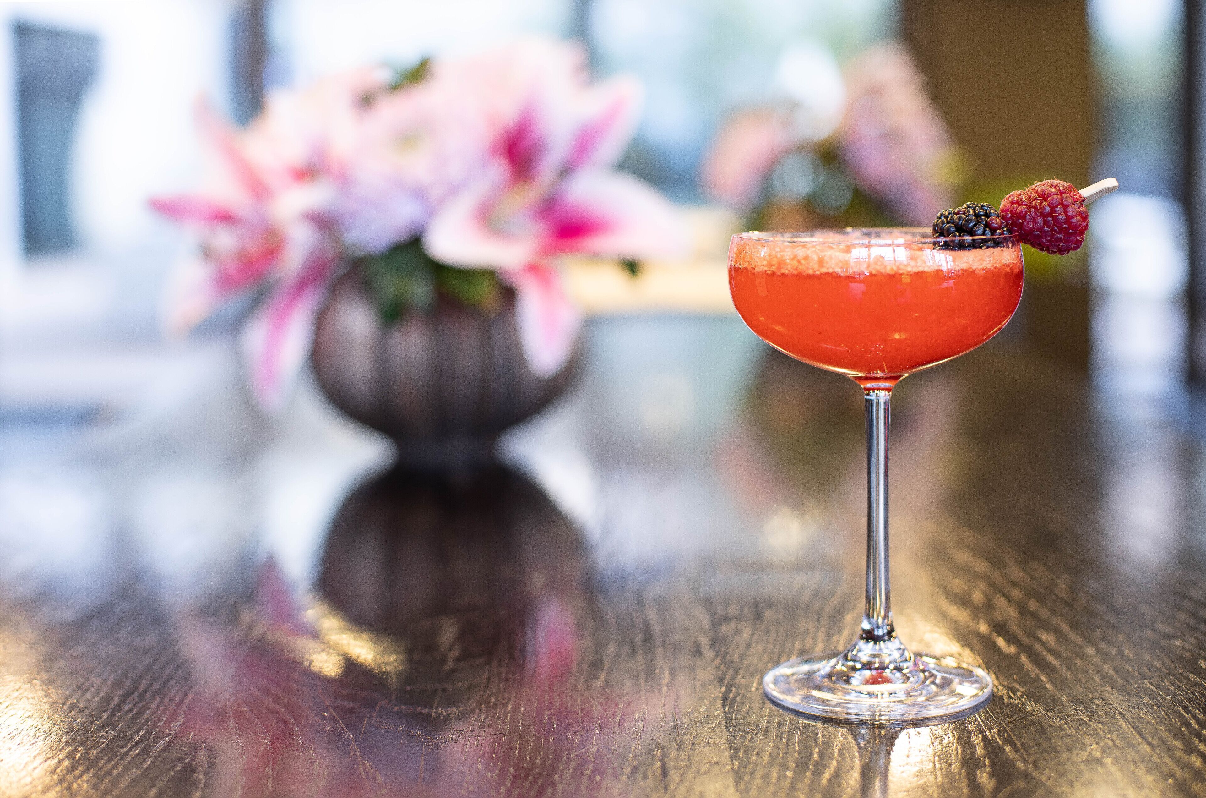 A cocktail in a martini glass with a garnish on a wooden table.