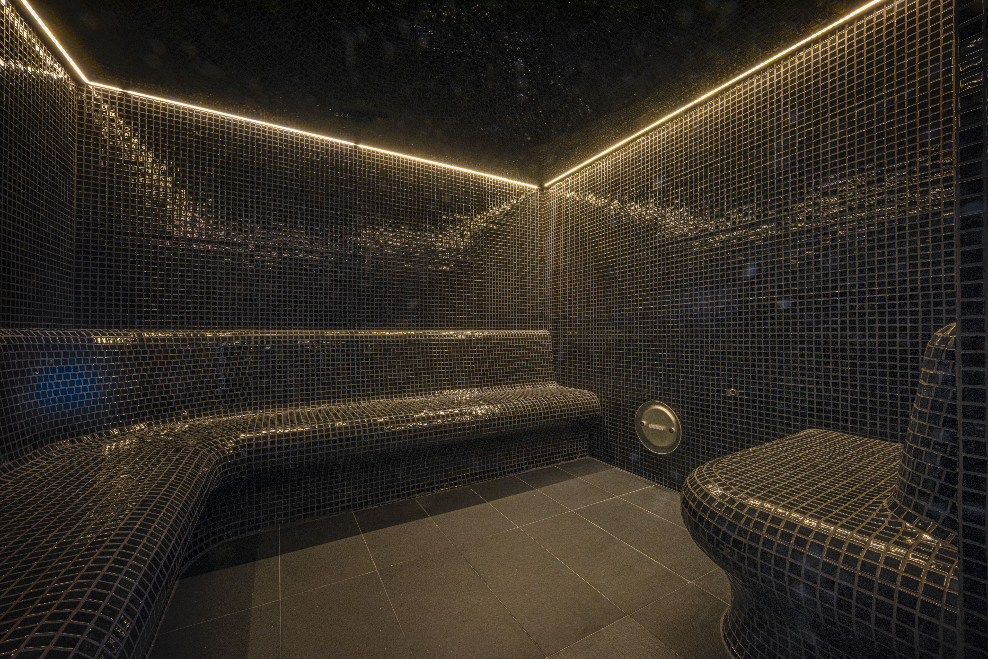 A modern bathroom with mosaic tile walls and a bench.