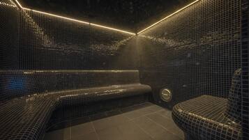 A modern bathroom with mosaic tile walls and a bench.