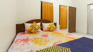 Une chambre à coucher avec une couvre-lit à motifs floraux, deux coussins à motifs géométriques et une couverture bleue.