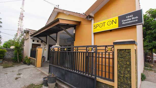Un bâtiment jaune avec un portail noir et une enseigne sur laquelle on peut lire : « SPOT ON 1842 Cevilla Bnb Residence ».
