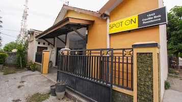 Un bâtiment jaune avec un portail noir et une enseigne sur laquelle on peut lire : « SPOT ON 1842 Cevilla Bnb Residence ».