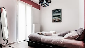 Ein modernes Schlafzimmer mit einem Bett, einem großen Spiegel, einem Gemälde und einer Heizung.