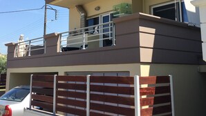 Ein mehrstöckiges Gebäude mit Balkon, Schornstein und einem parkenden Auto.