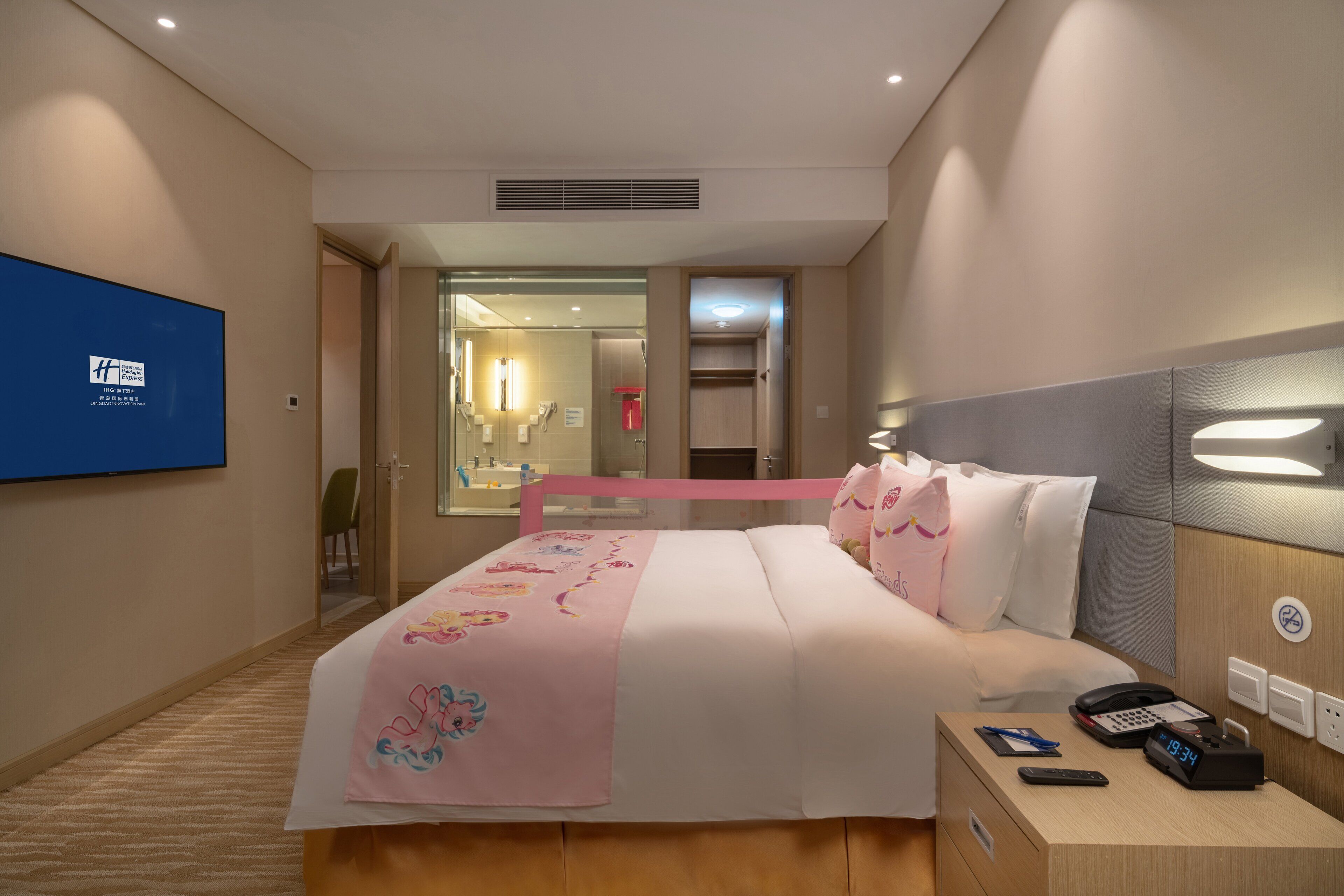 Una habitación de hotel con cama, mesita de noche y televisor en la pared.