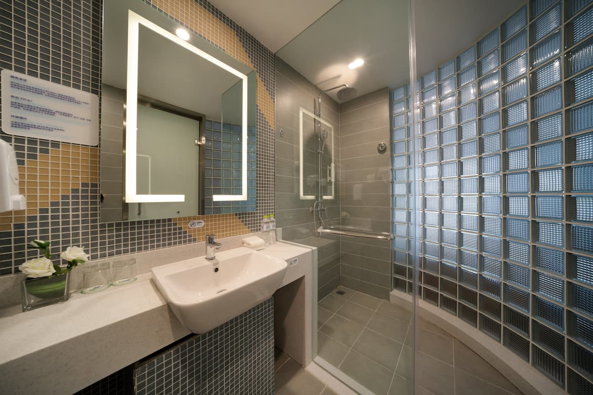 A modern bathroom with a glass shower enclosure, a large mirror, and a sink with a vanity.