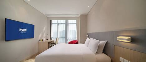 A hotel room with a bed, a desk, a chair, a TV, and a window.