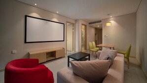 A modern living room with a beige sofa, a red armchair, a black coffee table, and a TV mounted on the wall. - Holiday Inn Express Qingdao Innovation Park by IHG (Qingdao)