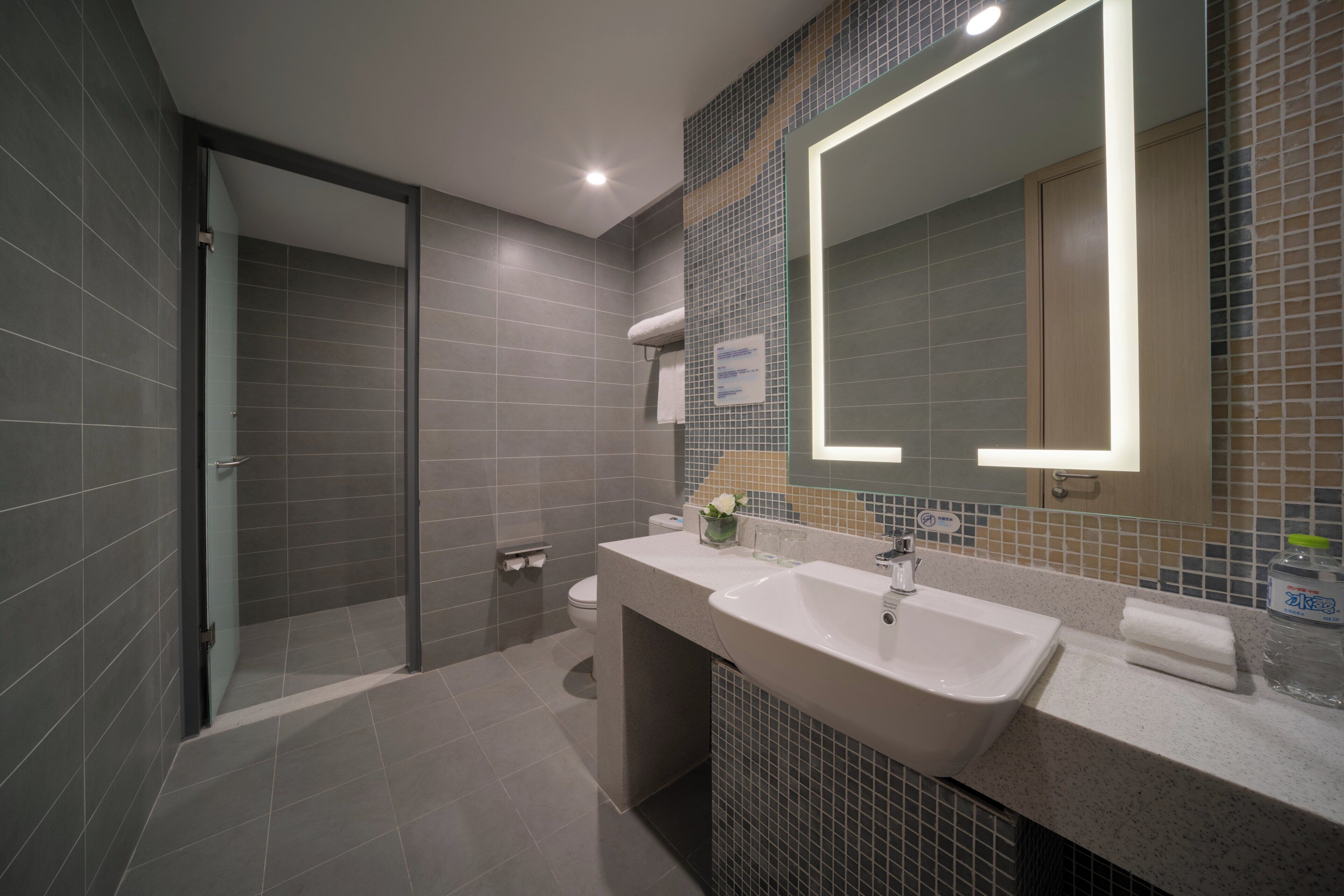 A modern bathroom with a large mirror, a sink, and a shower area.