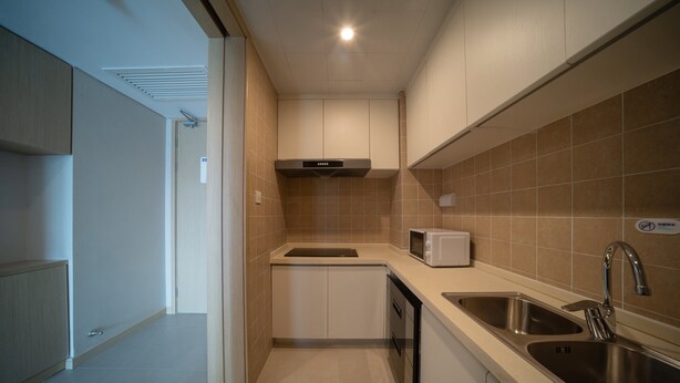 A modern kitchen with a microwave, sink, and ventilation hood. - Holiday Inn Express Qingdao Innovation Park by IHG (Qingdao)