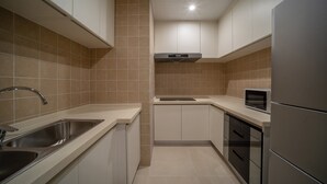 A modern kitchen with stainless steel appliances, a built-in microwave, and a double sink. - Holiday Inn Express Qingdao Innovation Park by IHG (Qingdao)