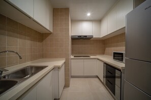 A modern kitchen with stainless steel appliances, a built-in microwave, and a double sink. - Holiday Inn Express Qingdao Innovation Park by IHG (Qingdao)