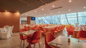 A spacious dining area with multiple tables and chairs, a modern ceiling design, and large windows allowing natural light. - Holiday Inn Express Qingdao Innovation Park by IHG (Qingdao)