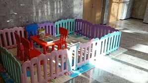 A play area with a colorful playpen, a table with a puzzle, and two chairs. - Holiday Inn Express Qingdao Innovation Park by IHG (Qingdao)