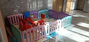 A play area with a colorful playpen, a table with a puzzle, and two chairs. - Holiday Inn Express Qingdao Innovation Park by IHG (Qingdao)