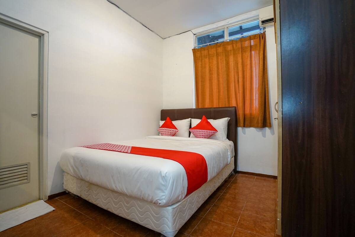 A neatly made bed with a white and red bedspread, two pillows, and a red throw blanket.