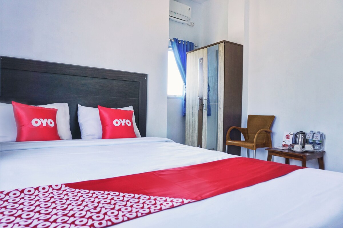 A hotel room with a bed, a wardrobe, a chair, and a table with amenities.