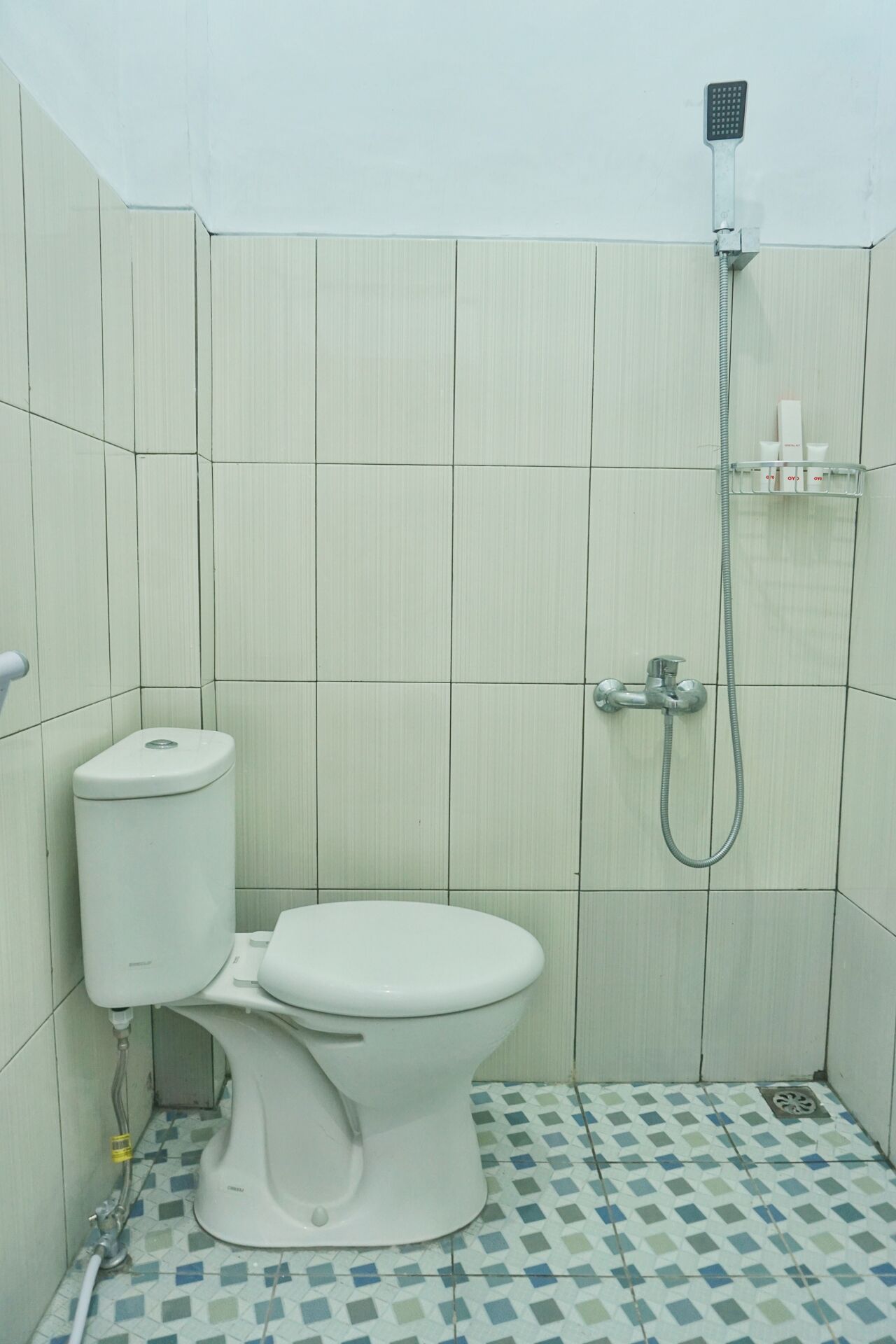 A small bathroom with a toilet, a shower, and a tiled floor.