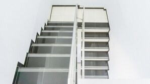 A staircase with a metal handrail and glass panels. - Hotel O Homiko (Pacitan)