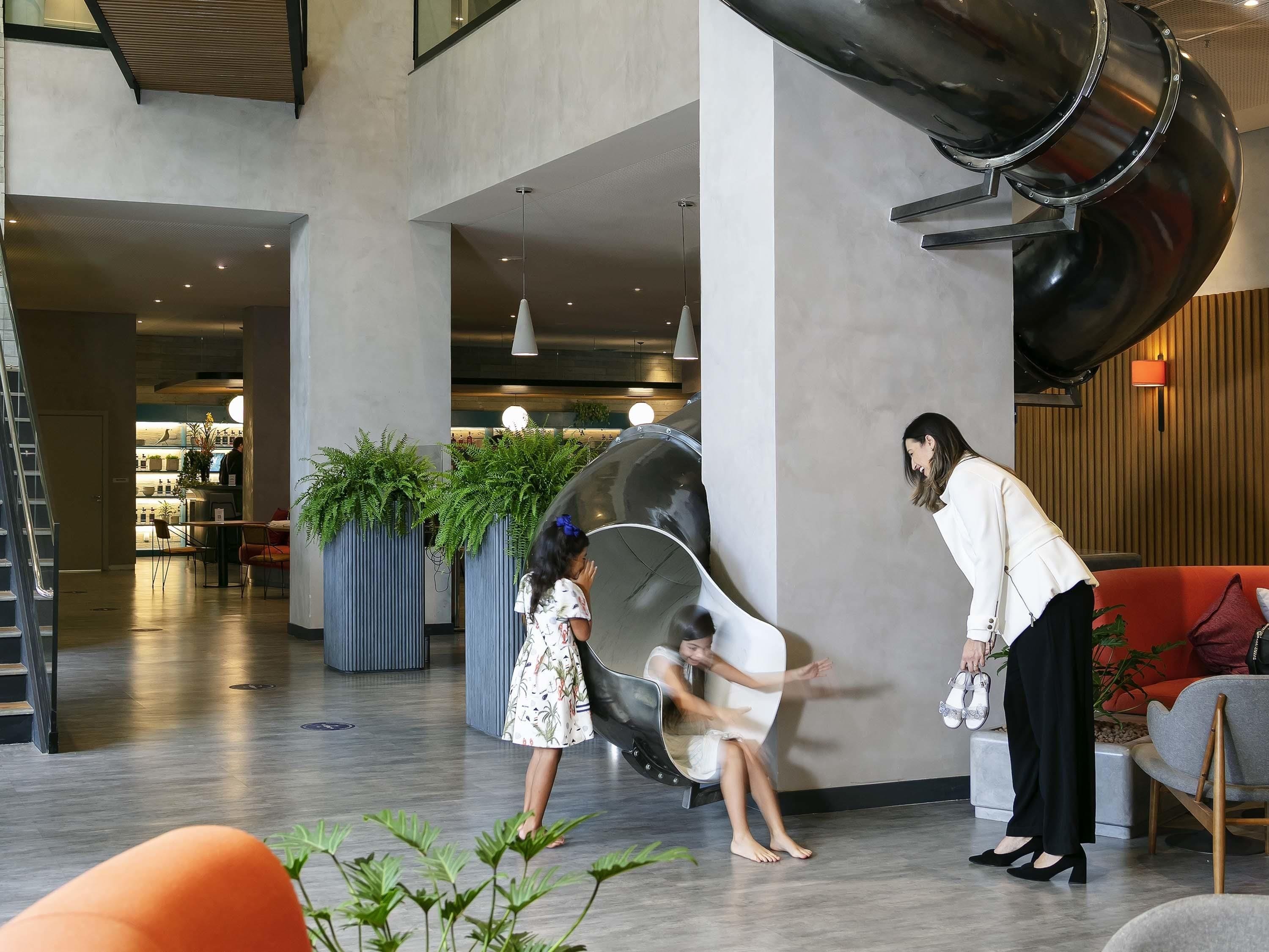 Eine großzügige Lobby mit modernem Design, inklusive einer großen, schwarzen Wendeltreppe, Sitzbereichen und Zimmerpflanzen.