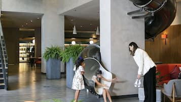 Eine großzügige Lobby mit modernem Design, inklusive einer großen, schwarzen Wendeltreppe, Sitzbereichen und Zimmerpflanzen.