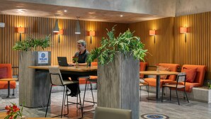A modern hotel lobby with a reception desk, seating area, and decorative plants. - Novotel Belo Horizonte Savassi (Belo Horizonte)