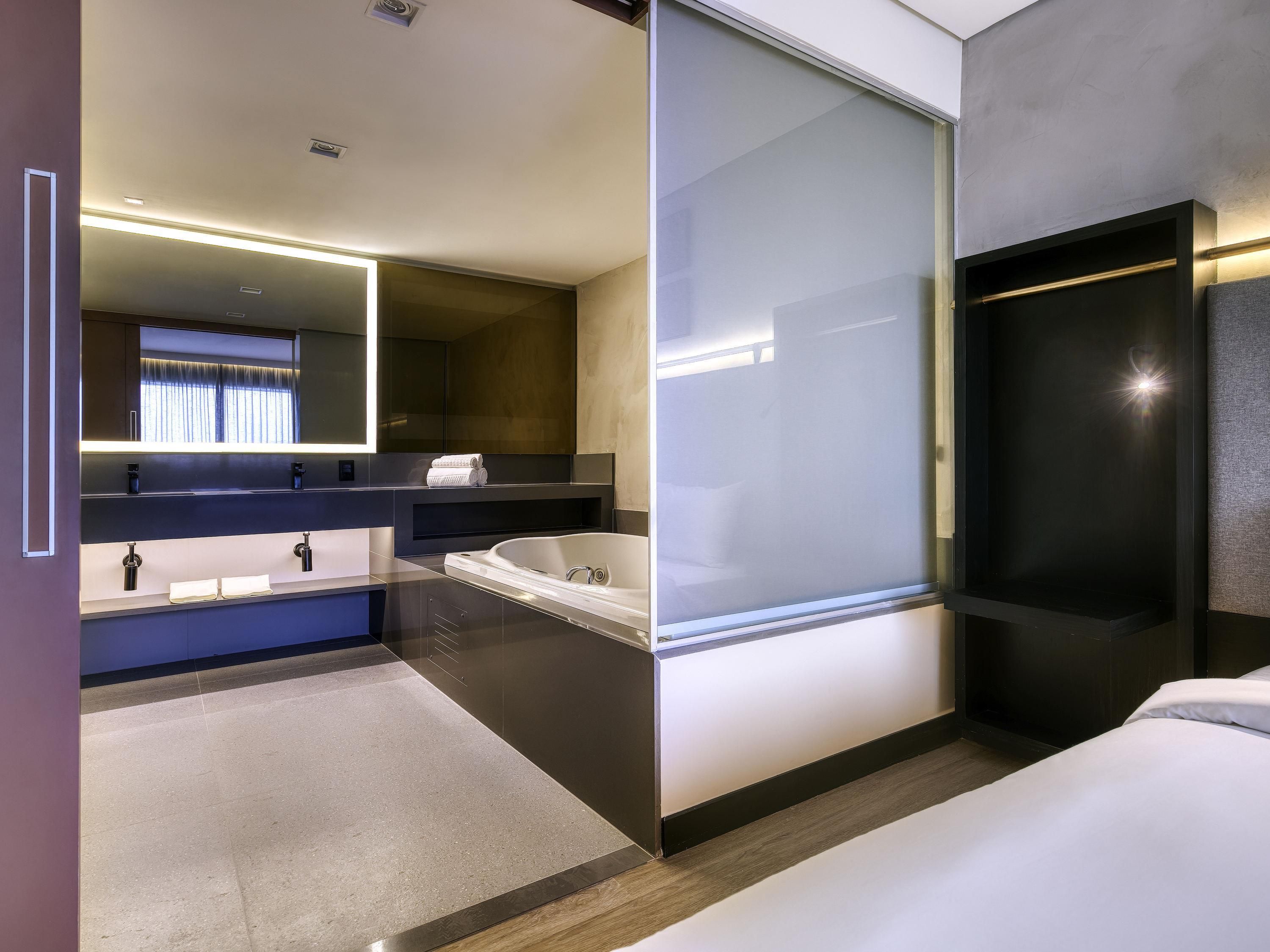 A modern bathroom with a large mirror, a bathtub, and a vanity with a sink.