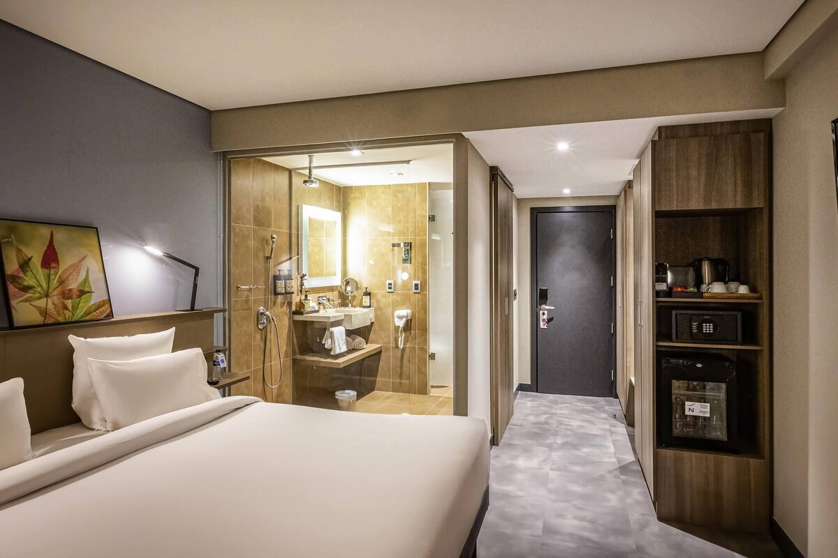 Une chambre d’hôtel comprenant un lit, une salle de bain avec douche, un lavabo et une armoire.