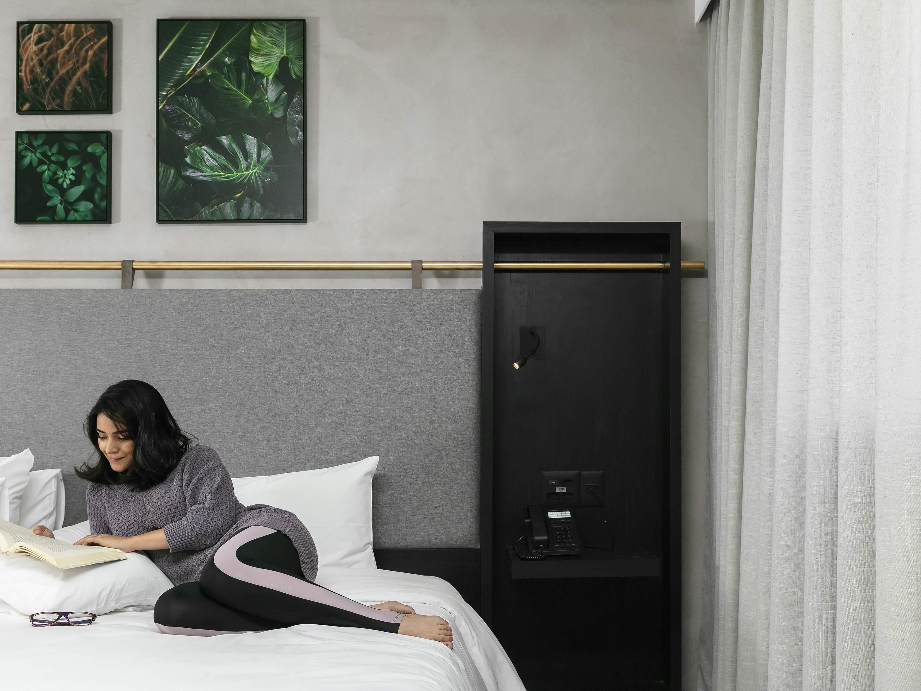 Una habitación de hotel con una cama, una mesita de noche con teléfono y un armario empotrado.