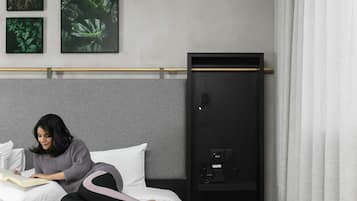 Una habitación de hotel con una cama, una mesita de noche con teléfono y un armario empotrado.