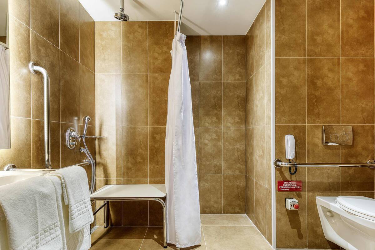 Un baño con ducha, inodoro y barra de apoyo.