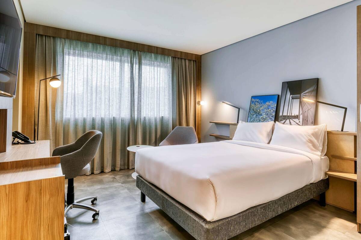 Une chambre d’hôtel équipée d’un lit, d’un bureau, de chaises et d’une télévision.