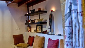 Ein gemütliches Wohnzimmer mit einem weißen Sofa, mehreren Kissen und Dekorationen auf Regalen.